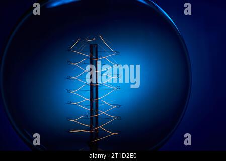 Electric vintage Edison light bulb with a spiral on a blue background. Retro style lamp. Stock Photo