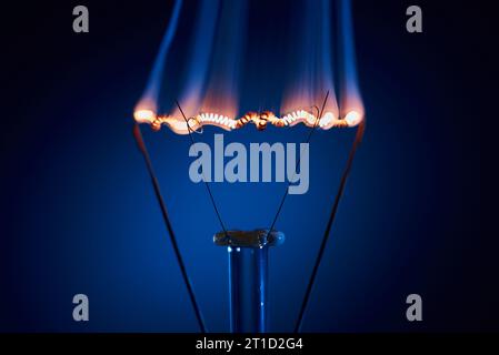 Electric bulb lamp with a burning spiral on a black background. Stock Photo