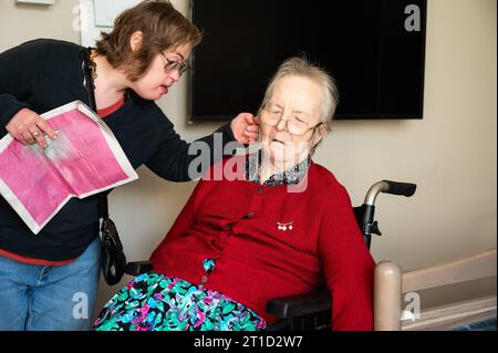 Daughter with Down Syndrome waking up her grandmother, sleeping in a wheelchair, Tienen, Flanders, Belgium Stock Photo