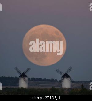 Barley full moon in the middle of two windmills, which are on a hill. Stock Photo