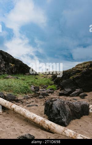 Tiny people in big landscape of beach and rock and cloudy sky Stock Photo