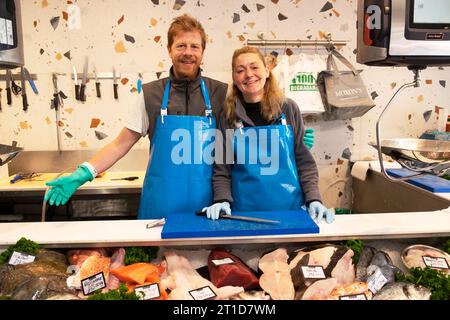 Workers behind the counter smiling showing variety of fish at Moxon's Fishmongers shop in Lordship Lane East Dulwich London England UK KATHY DEWITT Stock Photo