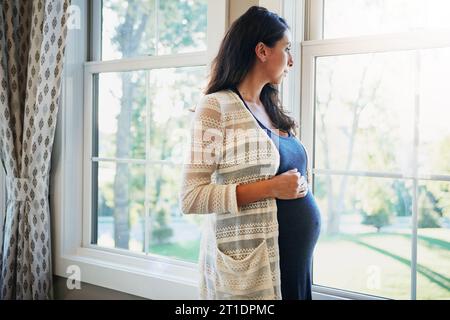 Pregnant woman, future and standing by window, think and trust in maternity, love and hands on stomach. Mother, healthy and care for baby, prenatal Stock Photo