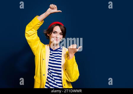 Photo of nice young woman wear yellow rain jacket gore tex indicate thumbs useful tips banner shopaholic isolated on blue color background Stock Photo