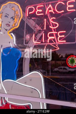 Front window of a neon sign shop with bullet hole in Albuquerque, New Mexico. Stock Photo