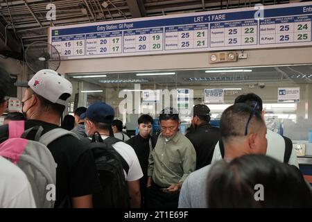 Manila, Philippines: commuters line up inside Gil Puyat Train Station to buy single journey tickets from Light Rail Transit 1 ticket booth. Busy metro. Stock Photo