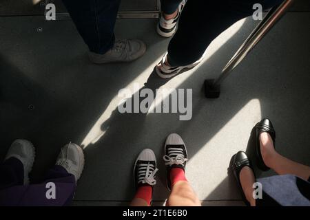 Feet of commuters with different footwear standing inside a train. Crossing paths with strangers from all walks of life concept. Shoes of people. Stock Photo