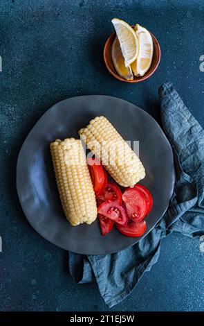Cooked white corn on the cob with tomatoes Stock Photo