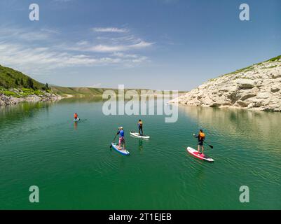 A group of tourists swims on SUP boards on a mountain lake. Stand Up Paddling. Mountain lake with azure water Stock Photo