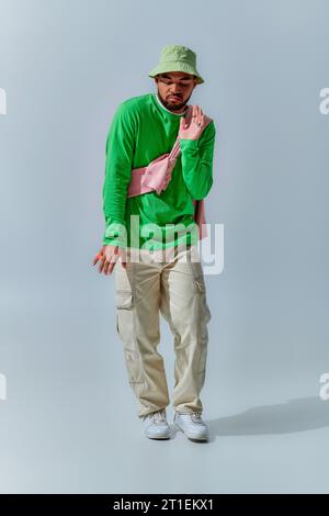 good looking young man with sweatshirt tied on his shoulders dancing on camera, fashion concept Stock Photo