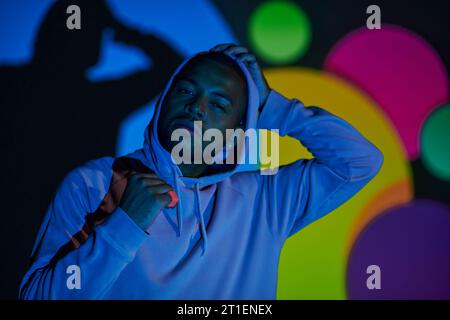 portrait of young man with hood on looking at camera in digital projector lights, fashion concept Stock Photo