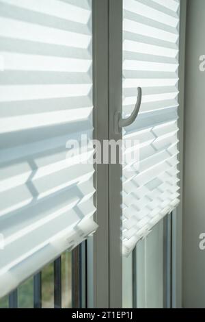 Fabric blinds on windows. Curtains jalousie blocking flow of heat into room, keeping apartment cool Stock Photo