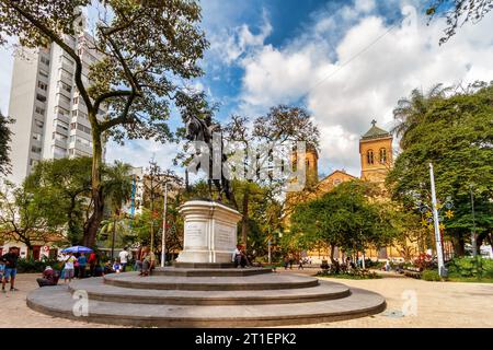 Medellin, Colombia - January 10, 2023: People walk and rest in the Parque de Bolivar in front of the Medellin cathedral Stock Photo