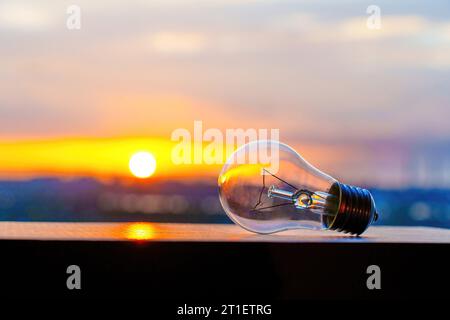 A light bulb set against the backdrop of a radiant sunset, symbolizing the concept of green energy and sustainability. Stock Photo