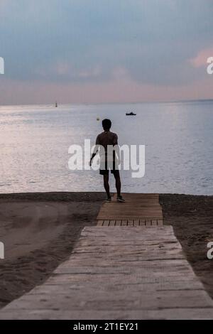 Sunrise on the promenade, Malaga, sunrise, man doing sports in the sand, looking at the sea, with his dog, Stock Photo