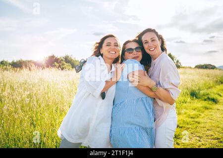 Portrait of three cheerful smiling women embracing during outdoor walking. They looking at the camera. Woman friendship, relations, and happiness conc Stock Photo