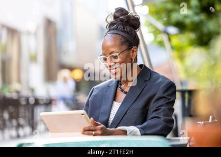 Portrait of happy businesswoman using tablet computer in outdoor cafe Stock Photo