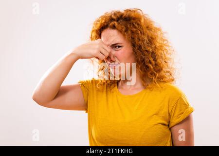 Shocked ginger woman doesn't like how something smells. Stock Photo