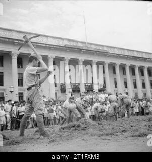 The British Reoccupation of Singapore A large crowd of civilians enjoy the spectacle of Japanese prisoners of war doing manual labour outside the Municipal Building in Singapore. Stock Photo