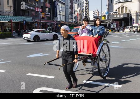 Tokyo, Japan - April 09: unidentified man pulling a rickshaw with two female passengers on the streets of Tokyo, Japan. Tokyo is the capital and the m Stock Photo