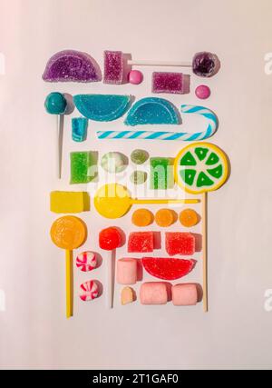 Creative colorful rainbow pattern from a jelly candy and lolipops on white background. Flat lay Stock Photo