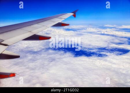 Passenger airplane wing with engines flying over Pacific ocean cloudscape to New Zealand. Stock Photo