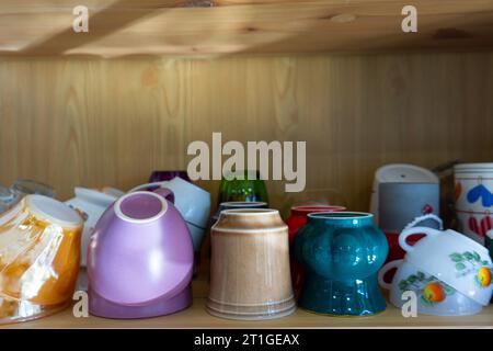 Cups in the kitchen cabinet. Colorful cups. Colorful cups used for tea and coffee. Kitchen cabinet layout. Stock Photo