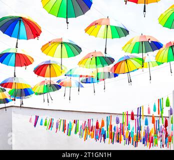 Colorful umbrellas and street decorations against a white sky and building in Metepec, Mexico. Stock Photo
