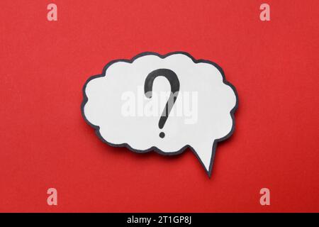 Paper speech bubble with question mark on red background, top view Stock Photo