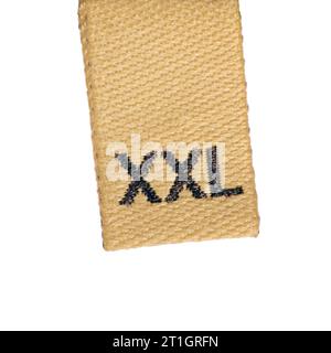 XXL size beige woven fabric clothing label garment tag, brown embroidered text, large detailed vertical isolated textured embroidery pattern macro Stock Photo