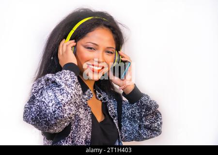A vertical closeup of a happy smiling Hispanic female enjoying music with headphones isolated on a white background Stock Photo
