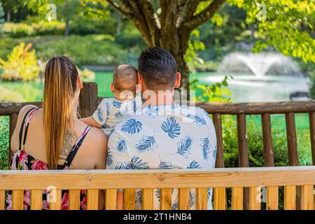 A family in Dijon's Japanese garden, a couple with a baby sitting on a bench. Le jardin japonais à Dijon en famille, couple avec un bébé assis sur un Stock Photo