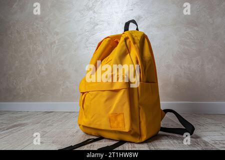 yellow backpack with raindrops on a white wall background close-up Stock Photo