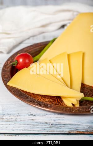 Aged cheese on a copper plate. Organic fresh cow cheddar on wood background Stock Photo