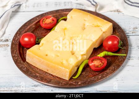Gruyere cheese on a copper plate. Slices of gruyere cheese on wooden background. Close up Stock Photo