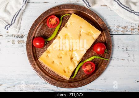 Gruyere cheese on a copper plate. Slices of gruyere cheese on wooden background. Top view Stock Photo