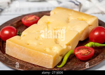 Gruyere cheese on a copper plate. Slices of gruyere cheese on wooden background Stock Photo