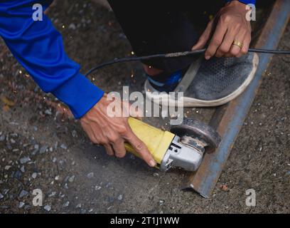 Industrial Worker Using Angle Grinder and Cutting a Metal Stock Photo
