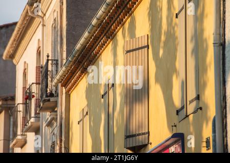 Shadows cast over shuttered windows on a home in the town of Quillan, Aude. Stock Photo