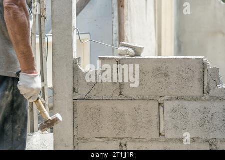 Hand of worker using hammer smashing and demolish on brick block wall at construction site Stock Photo