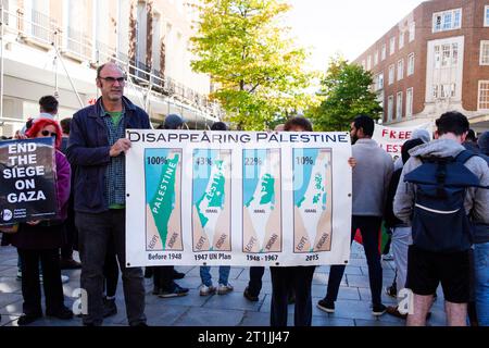 Free Palestine protest Exeter city centre - gentleman and hidden lady holding large 'disappearing Palestine' banner with map graphics and percentages Stock Photo