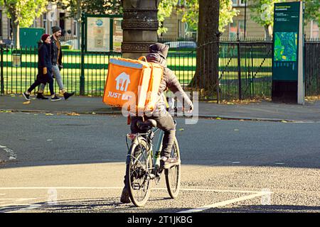 Glasgow, Scotland, UK. 14th October, 2023. UK Weather: Sunny autumnal colour saw the west end’s just eat delivery cyclist on university avenue  in the sun. Credit Gerard Ferry/Alamy Live News Stock Photo