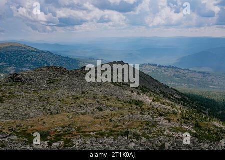 The sun's rays break through the clouds and illuminate the rocks and green forest. Natural landscape at summer day. Hike weather. Long trip in a natio Stock Photo