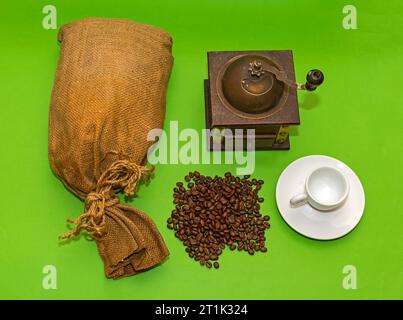 Pile of raw coffee beans with burlap sack and grinder on sides Stock Photo