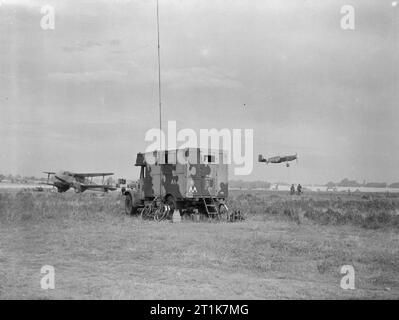Royal Air Force Army Co-operation Command, 1940-1943. A North American Mustang of No. 2 Squadron RAF, takes off from Sawbridgeworth, Hertfordshire, past a Commer Q2 mobile wireless van providing air to ground communications. To the left, a De Havilland Dragon Rapide communications aircraft is parked in on o fhe dispersals. Stock Photo