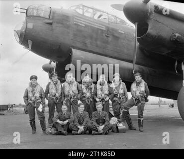Royal Air Force Bomber Command, 1942-1945. The air and ground crew of Avro Lancaster B Mark I, W4236 'QR-K', of 'A' Flight, No. 61 Squadron RAF, grouped by the nose of the aircraft at Syerston, Nottinghamshire, after it had completed 70 operational flights. Air crew, standing) left to right: Flying Officer F L Hewish, air bomber; Pilot Officer W H Eager RCAF, pilot and captain; Sergeant F R Stone, wireless operator; Sergeant L S Vanner, rear gunner; Sergeant H T Petts, navigator; Sergeant F R Sharrard, mid-upper gunner; Sergeant L Lawrence, flight engineer. Ground crew, (sitting) left to right Stock Photo