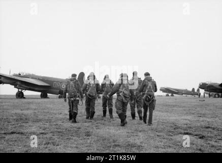 Royal Air Force Bomber Command, 1942-1945. The crew of an Avro Lancaster B Mark I of No. 61 Squadron RAF walk towards their aircraft at Syerston, Nottinghamshire, before taking off for a raid on Hamburg, Germany. Stock Photo