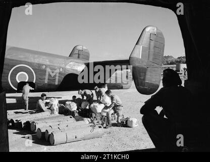 Royal Air Force- Italy,the Balkans and South-east Europe, 1942-1945. British soldiers and Yugoslav partisans transferring parachute containers and bundles of supplies from a lorry to Handley Page Halifax Mark II, BB338 'M' of No. 148 (Special Duties) Squadron RAF at Brindisi, Italy, before it takes off on a supply dropping mission to the Yugoslav National Liberation Army. BB338 was lost while returning from a similar operation on 5 December 1944. Stock Photo