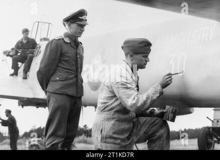 The Royal Air Force in Denmark Following the Liberation, 1945 German prisoners of war paint British markings on a Messerschmitt Bf 110 night fighter in preparation for the aircraft to be flown to England for evaluation, August 1945. Stock Photo