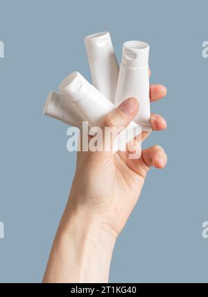 Hand holding many cream tubes, cosmetic samples Stock Photo